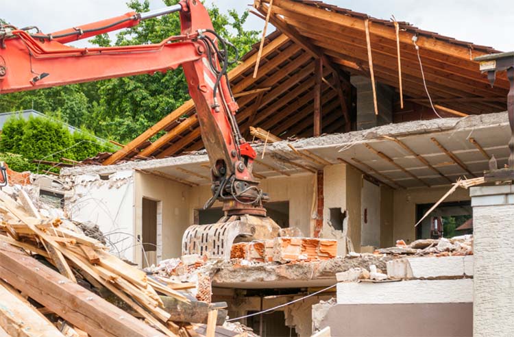 Excavator tearing down a house